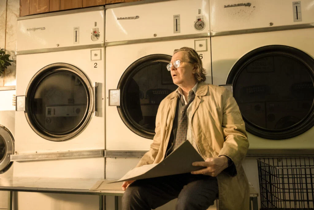 Ein Mann sitzt vor Waschmaschinen in einem Waschsalon. 