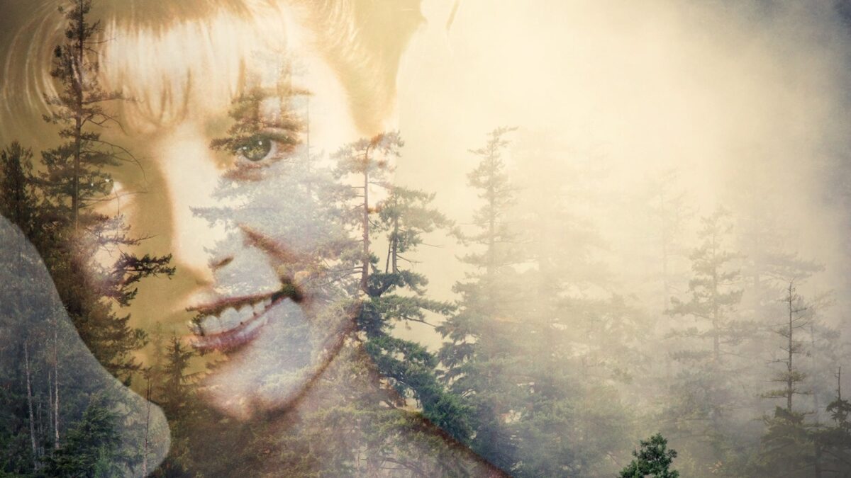 Eine Waldlandschaft, über die das transparente Porträt einer lächelnden Frau montiert ist.