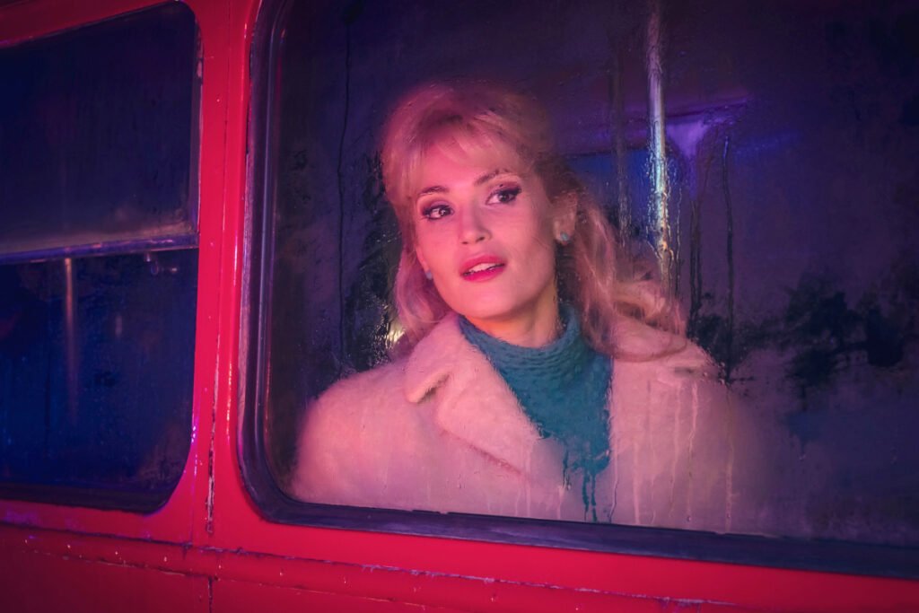 Eine Frau blickt erwartungsvoll aus dem Fenster eines roten Busses.
