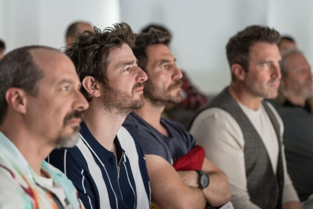 Vier Männer sitzen in einem Vortragsraum.