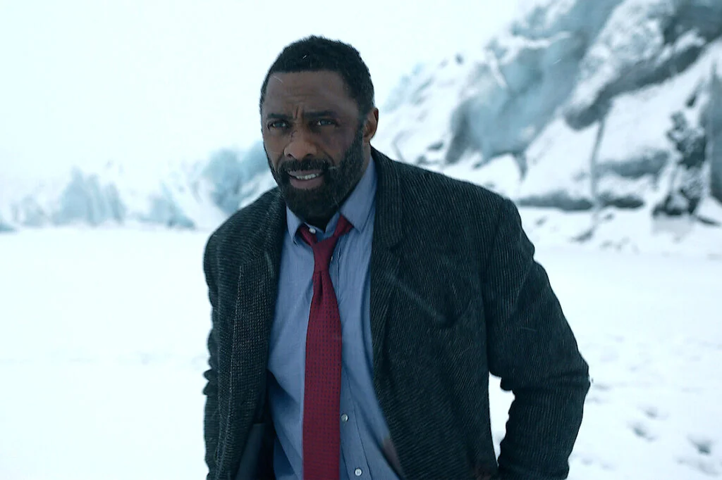 Ein Mann mit Jacke, Hemd und Krawatte in einer Schneelandschaft.