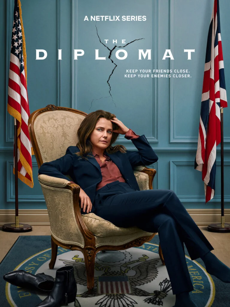 Serienposter mit Schriftzug. Eine Frau sitzt in einem Sessel. Neben ihr die britische und US-amerikanische Flagge.