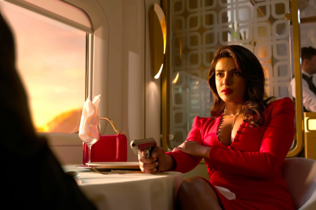 Eine Frau in rotem Kleid sitzt im Speisewagen eines Zugs mit gezückter Waffe.