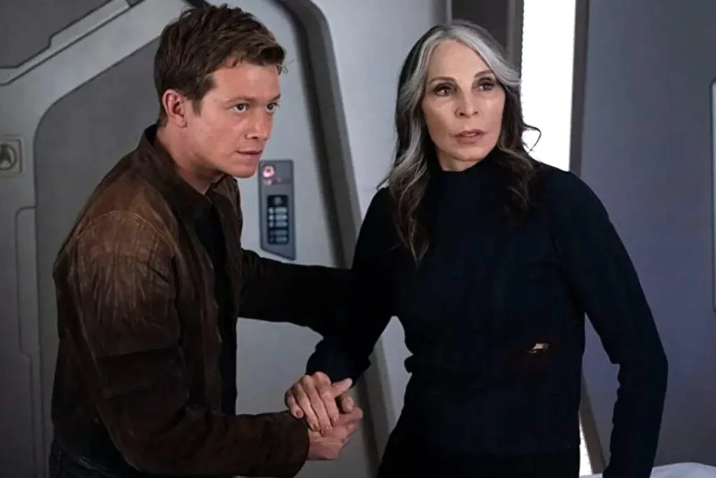 Eine Frau und ein junger Mann vor einer Türe auf einem Raumschiff.