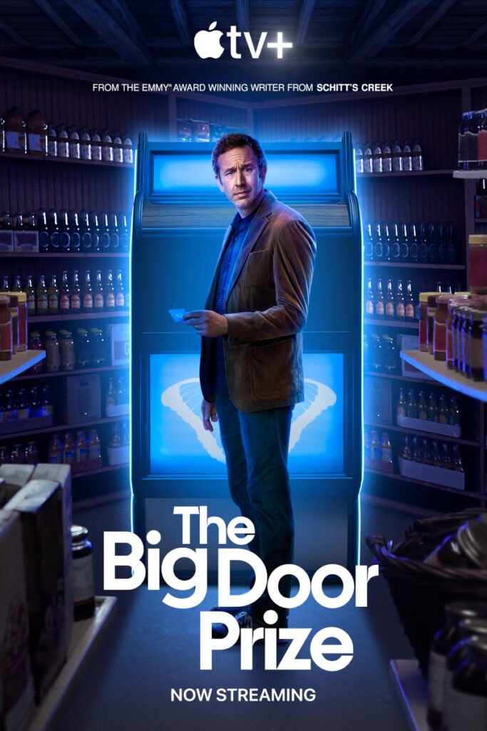 Serienposter mit Schriftzug. Ein Mann steht in einem Laden vor einer grossen blauleuchtenden Maschine. Er hält ein Kärtchen in der Hand und schaut irritiert in die Kamera.