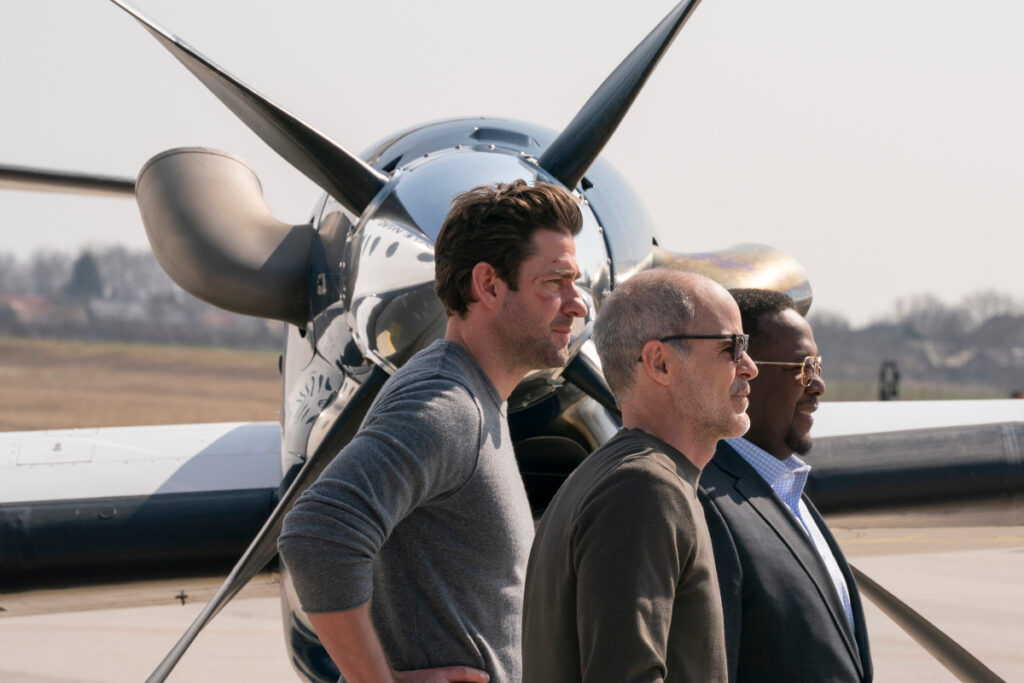 Drei Männer stehen vor dem Propeller eines Flugzeugs.