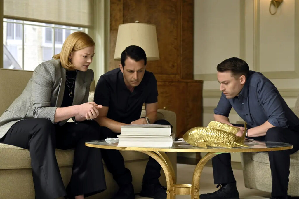 Eine Frau und zwei Männer sitzen um einen Tisch und schauen auf Dokumente.