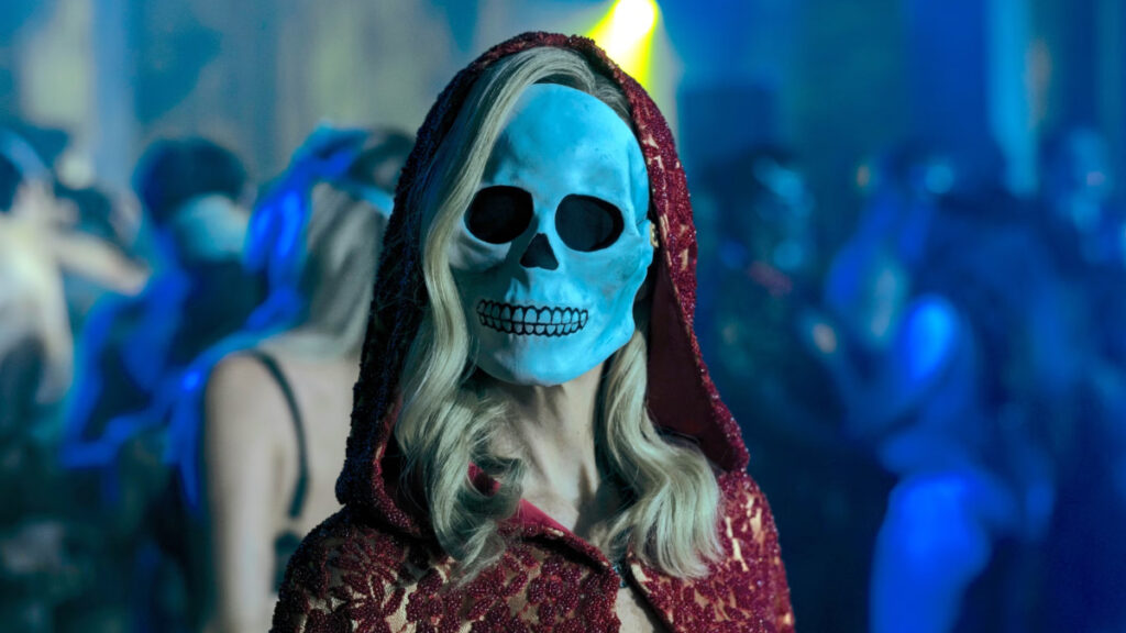 Eine Frau mit langem Haar vor dem Gesicht trägt sie eine Maske eines Totenschädels.