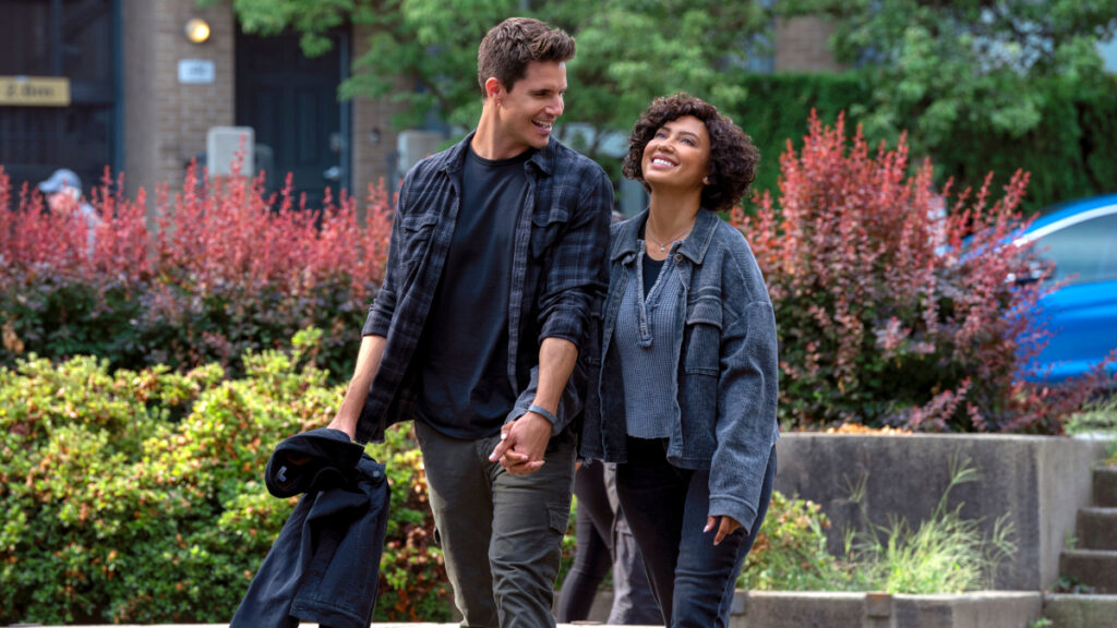 Ein Mann und eine Frau spazieren lächelnd durch einen Park.