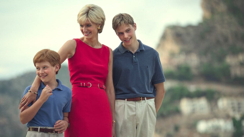 Eine blonde Frau in rotem Kleid, lächelnd. Flankiert von zwei Jungen, ebenfalls lächelnd.