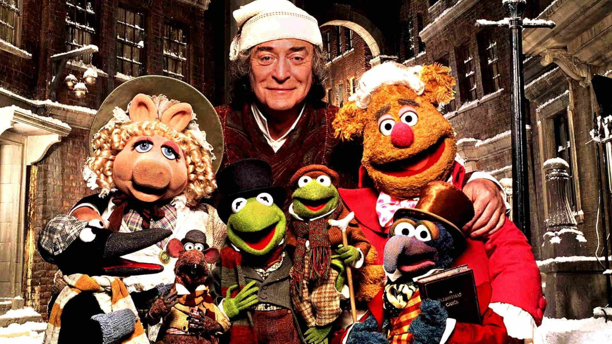 Eine Gruppe von Puppen - die Muppets - in ihrer Mitte ein Mann mit einer weissen Mütze. © TMDB