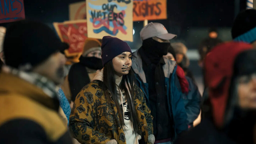 Eine junge Frau mit einer Gesichtsbemalung inmitten von Protestierenden. 