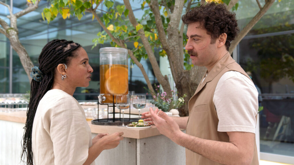 Ein Mann und eine Frau stehen an einem Getränkeausschank im Garten des Krankenhauses. 