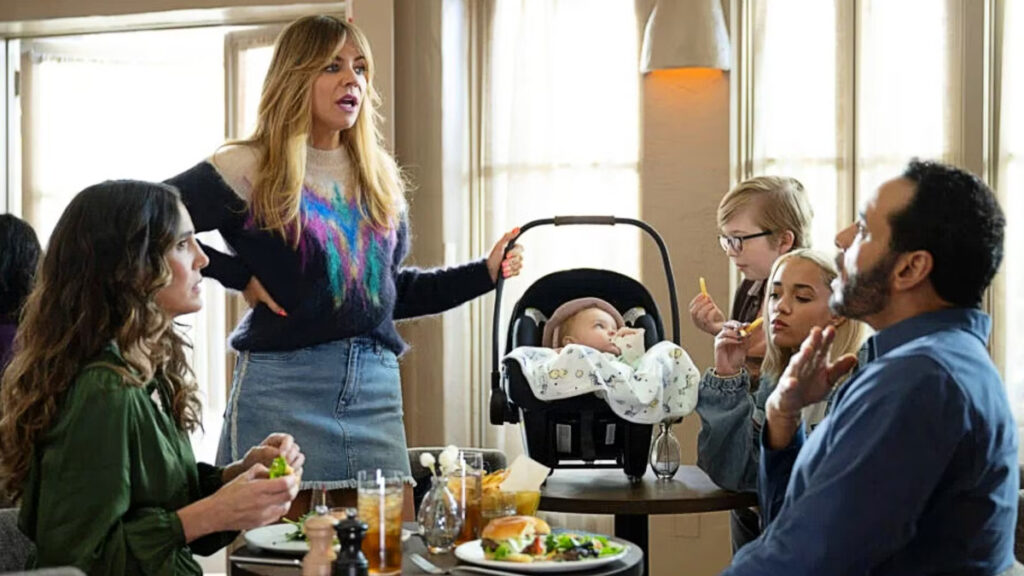 Ein Paar beim Burgeressen. Eine Frau mit zwei Kindern und einem Baby im Tragekorb steht neben ihrem Tisch.