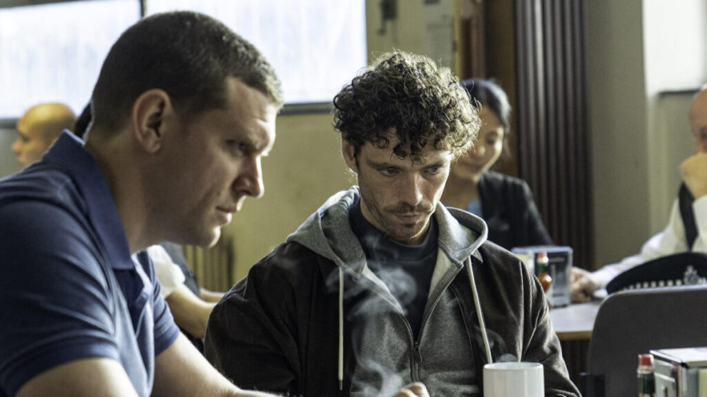 Zwei Männer sitzen an einem Tisch. Sie starren vor sich ins Leere.