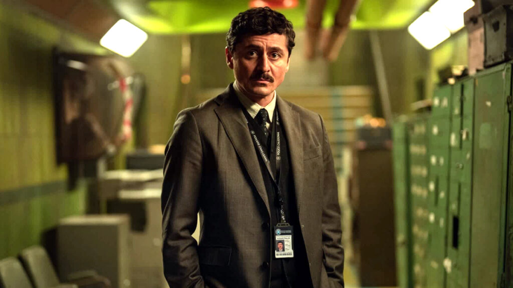 Ein Mann in einem mit Aktenschränken verstellten Raum ohne Tageslicht.