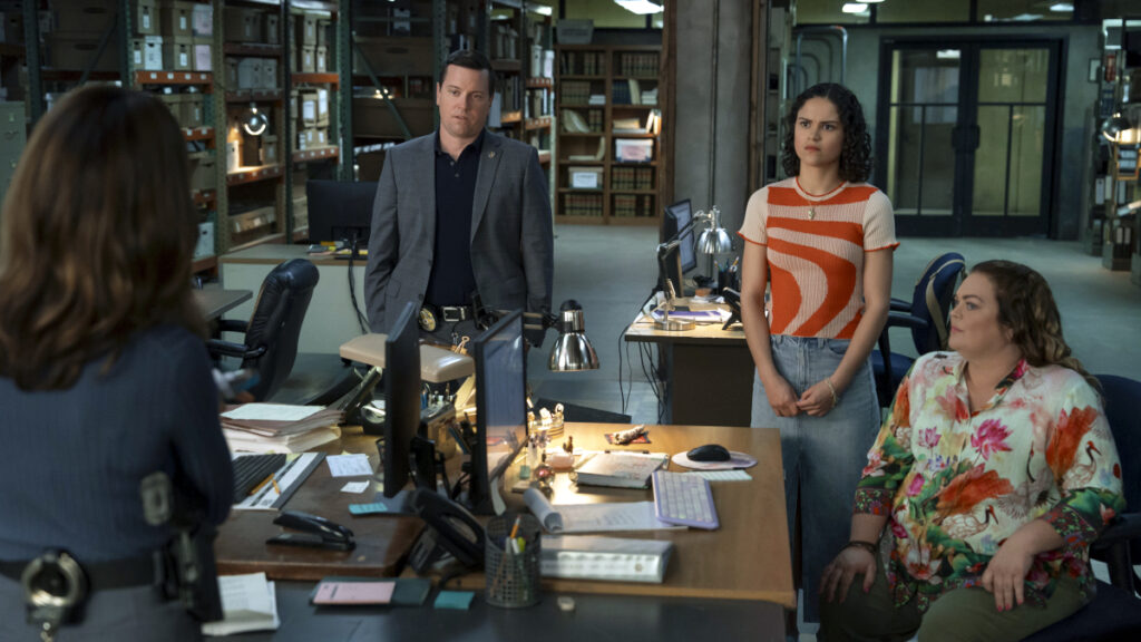 Drei Frauen und ein Mann um zwei Schreibtische versammelt. Im Hintergrund Archivregale.