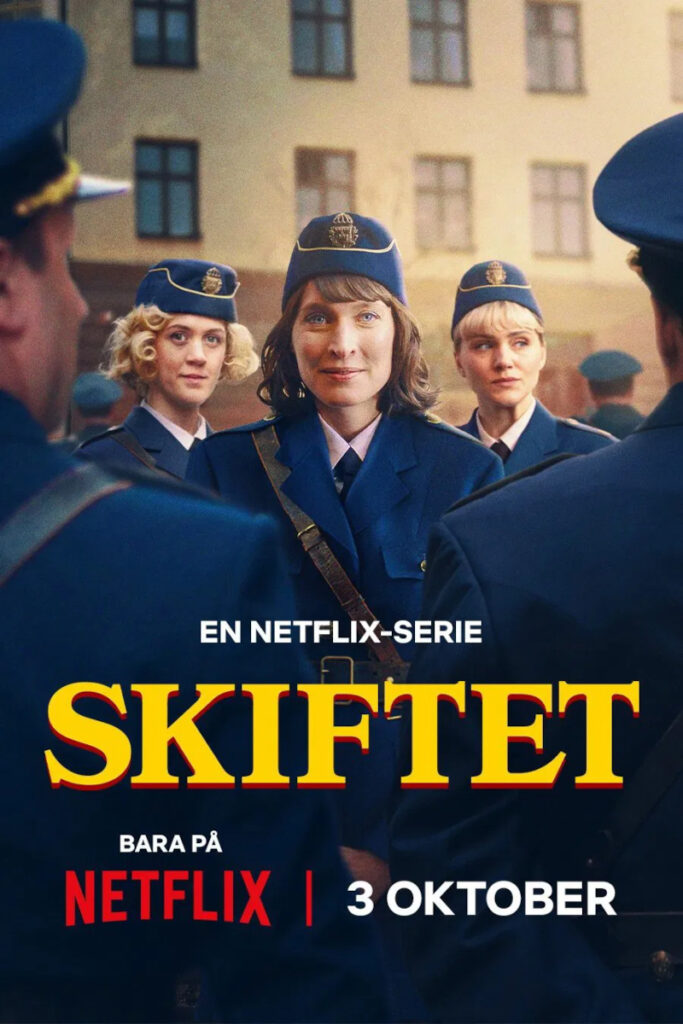 Eine Gruppe von Polizistinnen in blauen Uniformen steht vor einem beige-farbenen Gebäude. Die zentrale Frau trägt eine Mütze und schaut direkt in die Kamera. Über dem Bild steht der Titel «SKIFTET» in grossen gelben Buchstaben. Darunter der Hinweis auf die Veröffentlichung auf Netflix am 3. Oktober