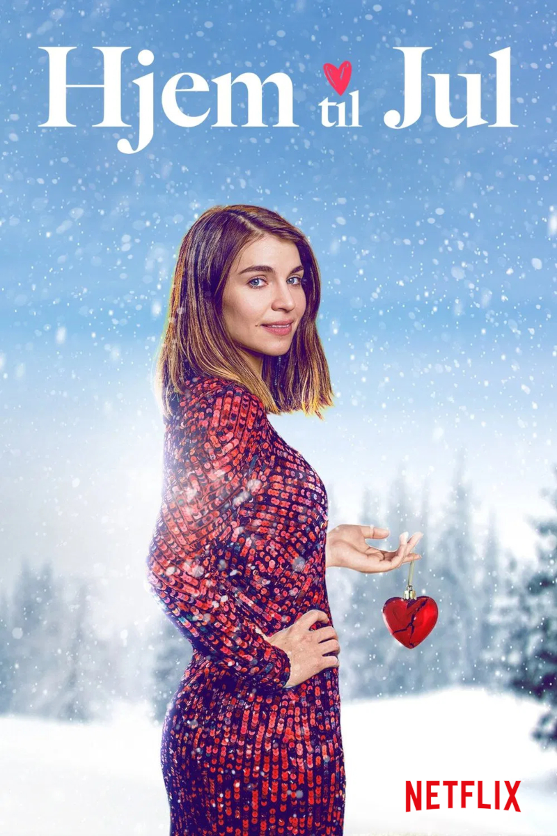Eine Frau in einem roten Kleid steht im Schnee. Sie hält ein rotes Herzornament in der Hand. Oben steht der Titel «Hjem til Jul». Im Hintergrund sind verschwommene verschneite Bäume zu sehen. Das Netflix-Logo ist unten rechts platziert.