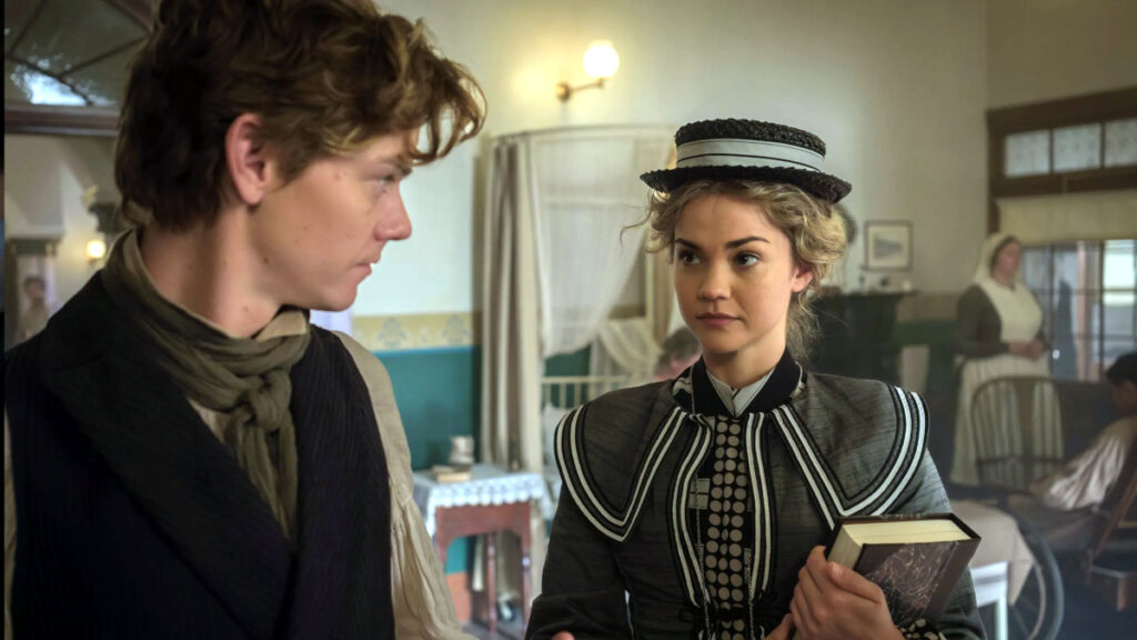 Ein Mann und eine Frau in viktorianischer Kleidung stehen sich in einem Krankenhauszimmer gegenüber. Die Frau trägt vornehme Kleider und hält ein Buch, während der Mann in dunkler Kleidung mit Schal zu ihr blickt.