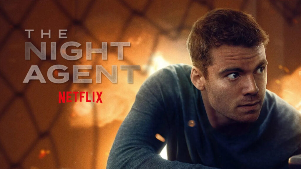 Netflix-Promobild für «The Night Agent»: Ein Mann mit kurzen braunen Haaren in grauem Pullover blickt über die Schulter. Im Hintergrund sind warme, orangefarbene Lichter zu sehen. Der Titel der Serie steht links im Bild.