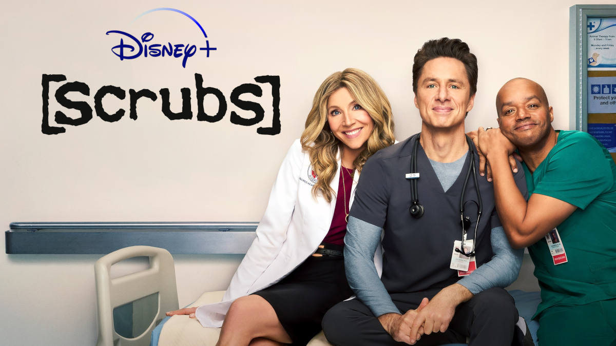 Drei Personen in Arztkitteln posieren lächelnd in einem Krankenhausflur vor einem Patientenbett. Links eine Frau im weissen Kittel, in der Mitte ein Mann mit Stethoskop, rechts ein Mann in grünen Scrubs. Oben das Disney+ Logo und der Serientitel «Scrubs».