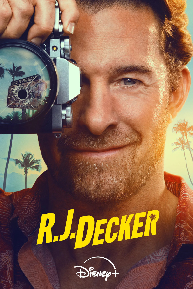 **Alt-Text:**Poster der Disney+-Serie «R.J. Decker»: Ein lächelnder Mann mit Dreitagebart hält eine Kamera mit einem Einschussloch in der Linse vors Gesicht. Im Hintergrund Palmen und warmes Sonnenlicht – Urlaubsatmosphäre in Florida.