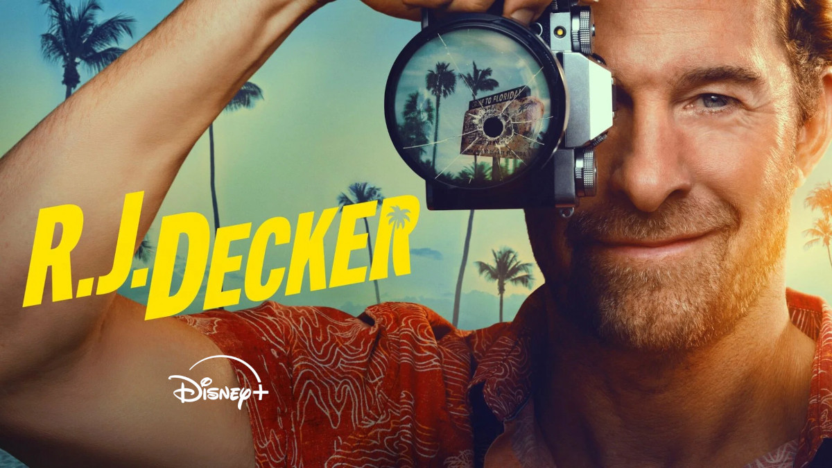 **Alt-Text:**Poster der Disney+-Serie «R.J. Decker»: Ein lächelnder Mann mit Dreitagebart hält eine Kamera mit einem Einschussloch in der Linse vors Gesicht. Im Hintergrund Palmen und warmes Sonnenlicht – Urlaubsatmosphäre in Florida.